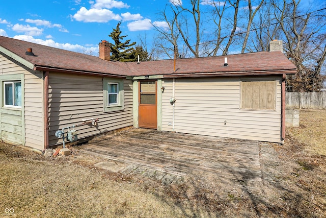 view of front facade featuring a deck, fence, and a chimney