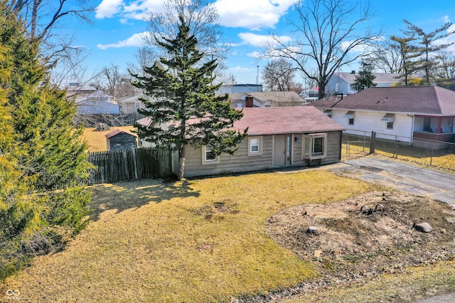 view of front of house featuring a residential view, fence, and a front lawn