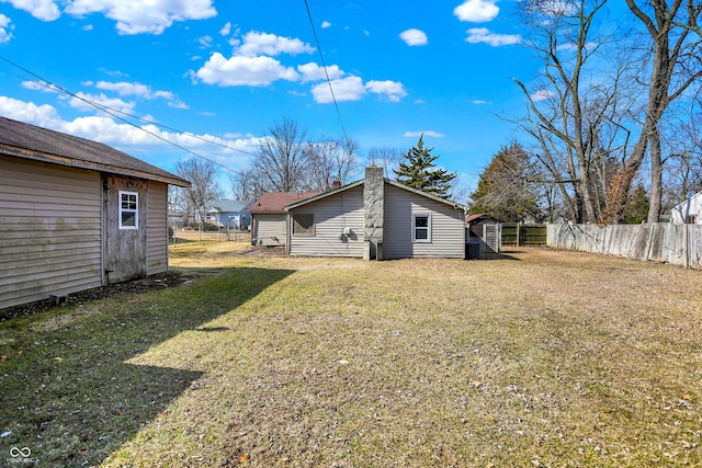 rear view of house with a chimney, a lawn, fence, a shed, and an outdoor structure