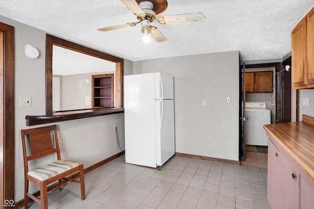 kitchen with washer / dryer, baseboards, a ceiling fan, freestanding refrigerator, and a textured ceiling