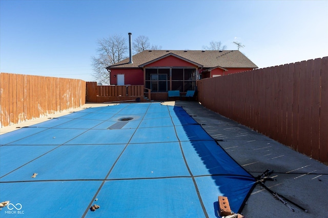 view of swimming pool with a sunroom and a fenced backyard