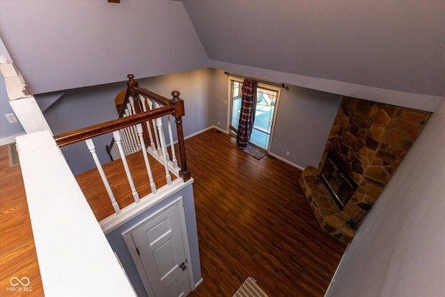 stairway featuring a fireplace, baseboards, vaulted ceiling, and wood finished floors