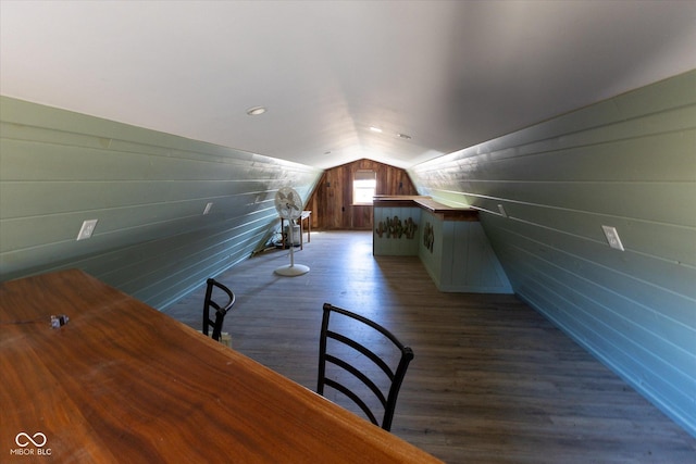 additional living space with vaulted ceiling, dark wood-style flooring, and wooden walls