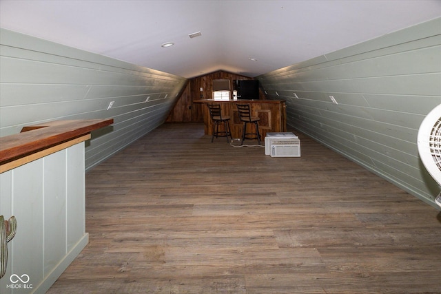 bonus room with lofted ceiling, wooden walls, and wood finished floors