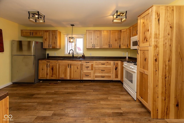 kitchen with white appliances, dark countertops, dark wood-style floors, decorative light fixtures, and a sink