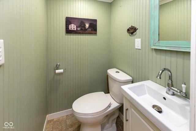 bathroom with stone finish flooring, vanity, toilet, and baseboards