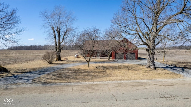 view of yard with driveway, a garage, and an outbuilding