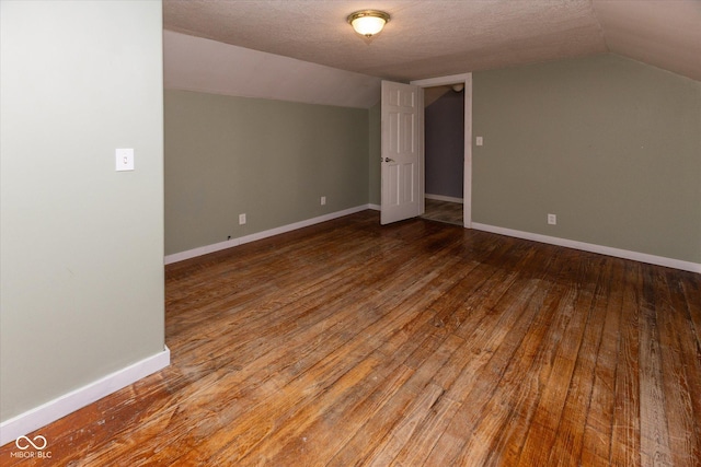 bonus room with a textured ceiling, lofted ceiling, hardwood / wood-style flooring, and baseboards