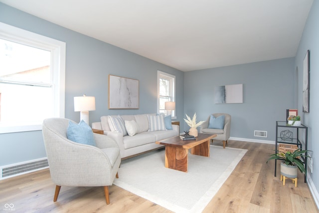 living area with light wood finished floors, visible vents, and baseboards