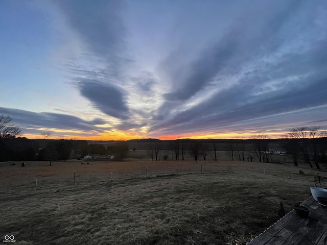 yard at dusk featuring a rural view