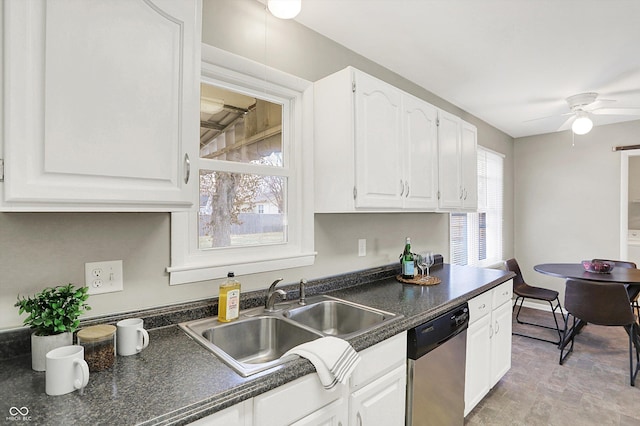 kitchen with dark countertops, dishwasher, white cabinetry, and a sink