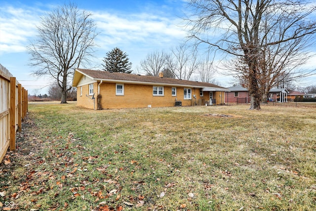 back of property featuring brick siding, fence, and a lawn