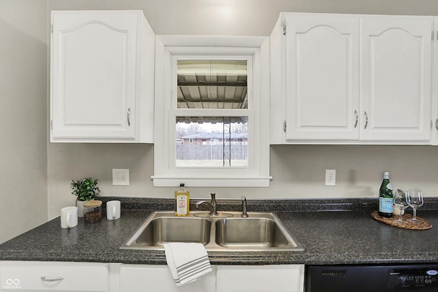 kitchen featuring black dishwasher, dark countertops, a sink, and white cabinets