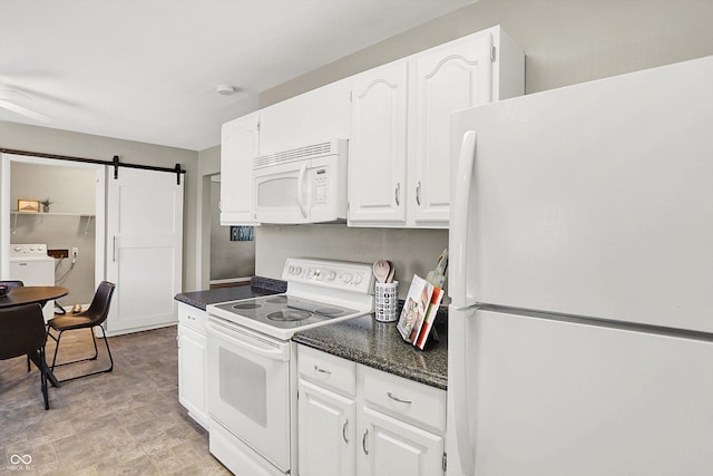 kitchen featuring white appliances, a barn door, washer / dryer, dark stone countertops, and white cabinetry