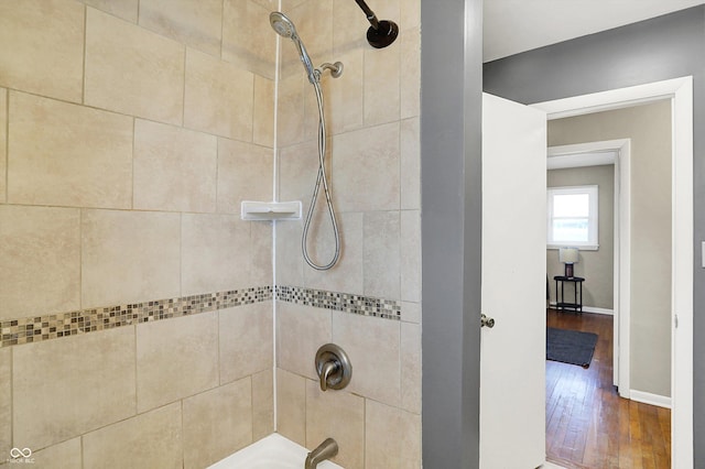 full bathroom featuring baseboards, wood finished floors, and shower / bathing tub combination