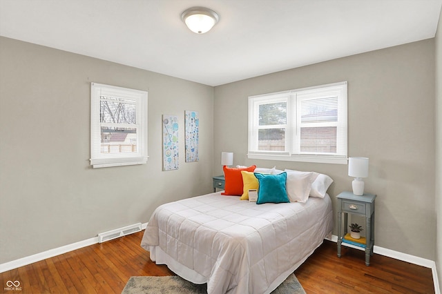 bedroom with wood-type flooring, visible vents, baseboards, and multiple windows