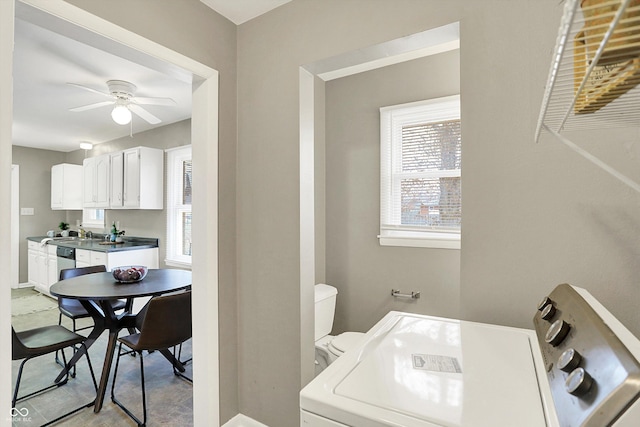 bathroom featuring washer / dryer, baseboards, a ceiling fan, toilet, and a sink