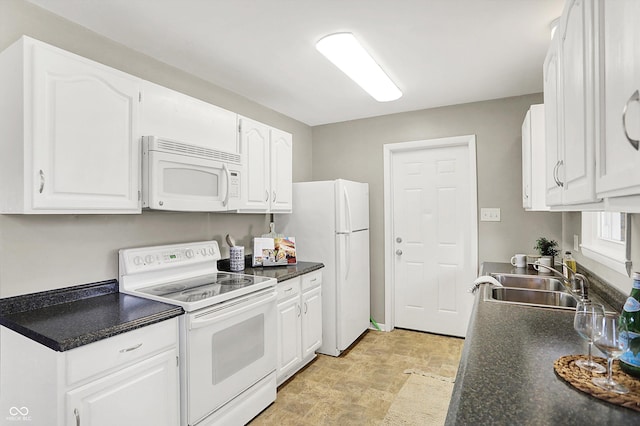 kitchen with dark countertops, white appliances, white cabinets, and a sink