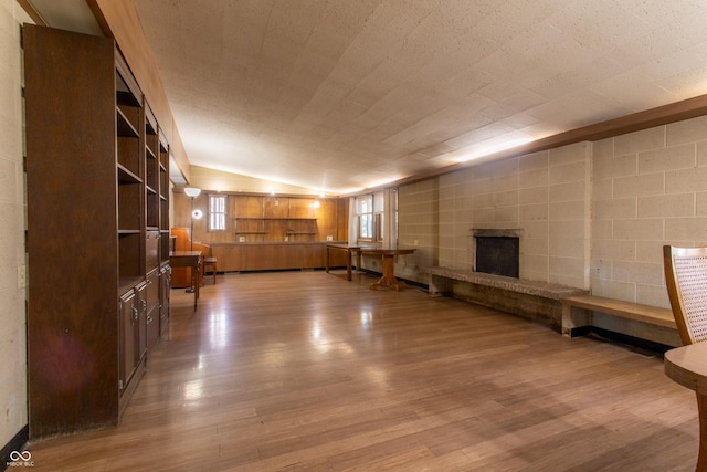 unfurnished room featuring lofted ceiling, a large fireplace, and wood finished floors