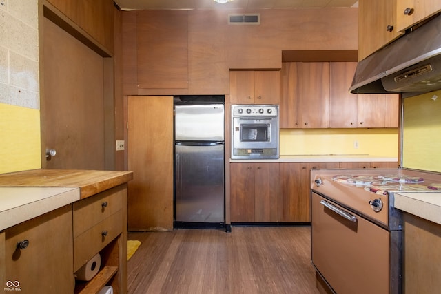 kitchen with visible vents, appliances with stainless steel finishes, wood finished floors, light countertops, and under cabinet range hood