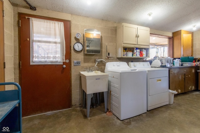 clothes washing area featuring independent washer and dryer, a sink, cabinet space, and concrete block wall