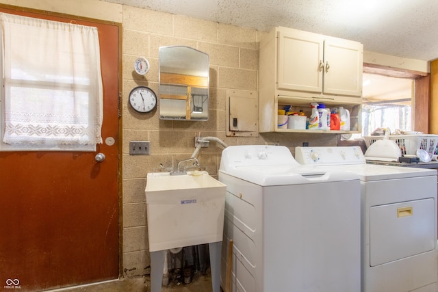 washroom featuring a sink, washing machine and clothes dryer, and cabinet space