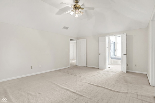 unfurnished bedroom featuring lofted ceiling, ensuite bathroom, light colored carpet, visible vents, and baseboards