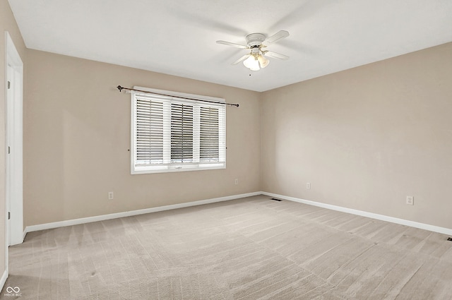 spare room with light carpet, ceiling fan, visible vents, and baseboards