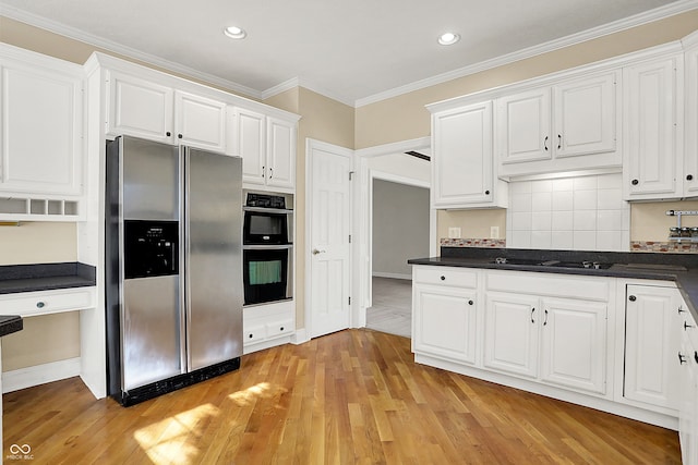 kitchen featuring white cabinets, dark countertops, stainless steel appliances, and crown molding