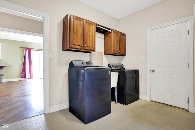 washroom featuring washer and dryer, cabinet space, and baseboards