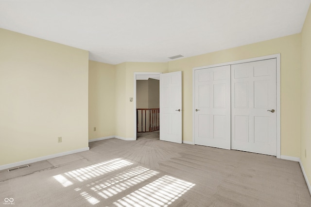 unfurnished bedroom with baseboards, visible vents, a closet, and light colored carpet