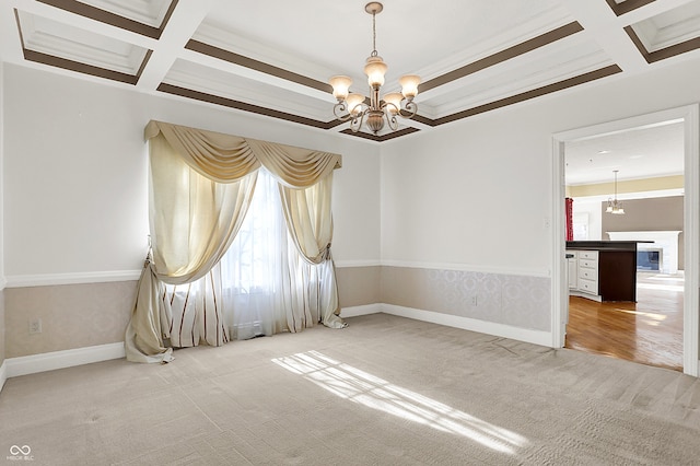 spare room featuring carpet floors, coffered ceiling, and an inviting chandelier