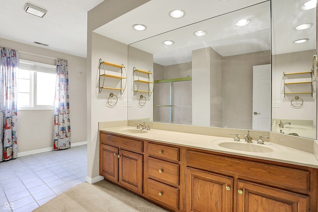 full bath featuring double vanity, a stall shower, tile patterned flooring, and a sink