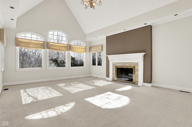 unfurnished living room with visible vents, a high end fireplace, carpet flooring, high vaulted ceiling, and baseboards