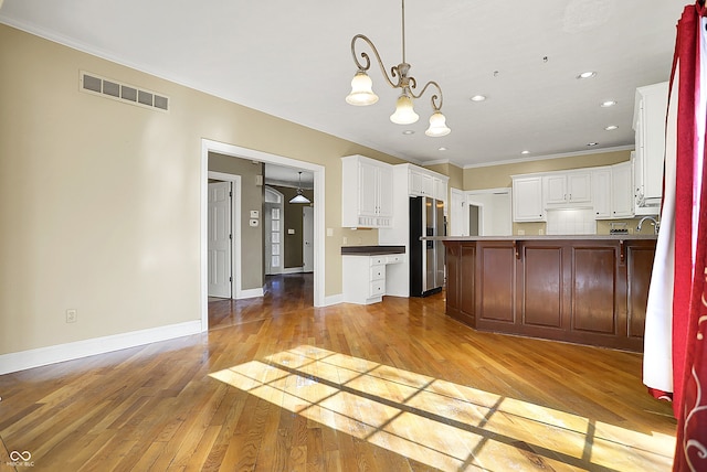 kitchen featuring light wood-style flooring, stainless steel refrigerator with ice dispenser, visible vents, and a notable chandelier