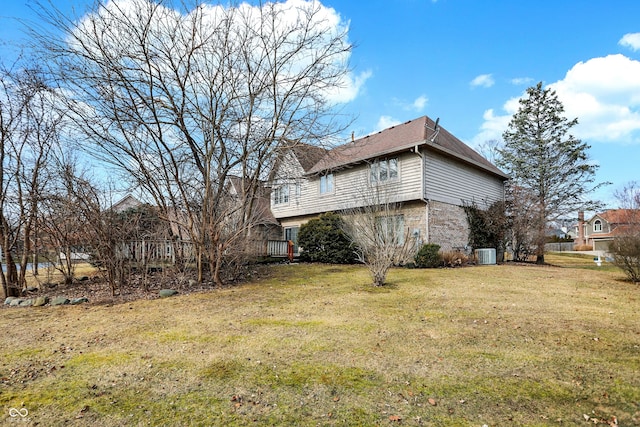 view of property exterior with central air condition unit, brick siding, and a yard