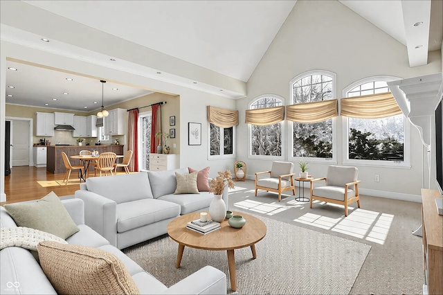 living room with high vaulted ceiling, recessed lighting, light wood finished floors, and baseboards