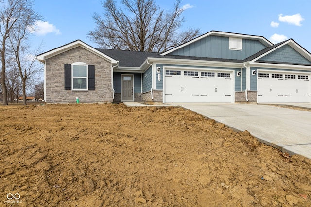 view of front of house featuring a garage, stone siding, driveway, and board and batten siding