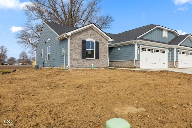 view of front of home with an attached garage, cooling unit, stone siding, concrete driveway, and board and batten siding