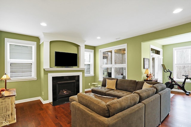 living area with dark wood-type flooring, recessed lighting, a fireplace with flush hearth, and baseboards