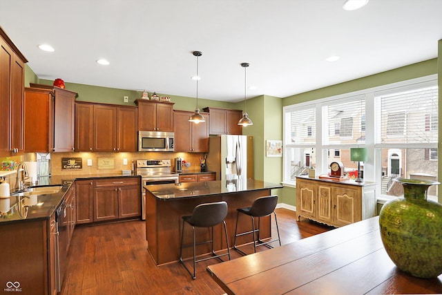 kitchen featuring dark countertops, appliances with stainless steel finishes, backsplash, and a sink