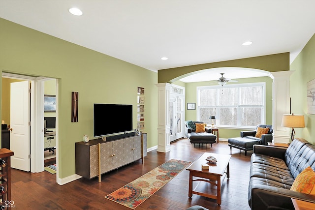 living area featuring ornate columns, a ceiling fan, arched walkways, and wood finished floors