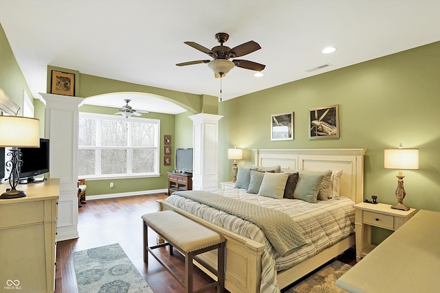 bedroom featuring arched walkways, recessed lighting, visible vents, dark wood finished floors, and decorative columns