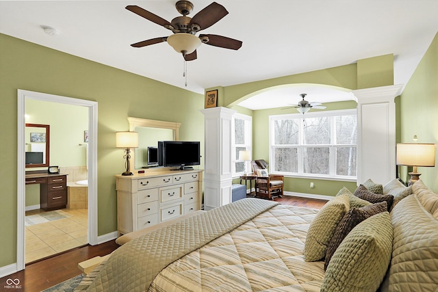 bedroom featuring ensuite bath, decorative columns, baseboards, and wood finished floors