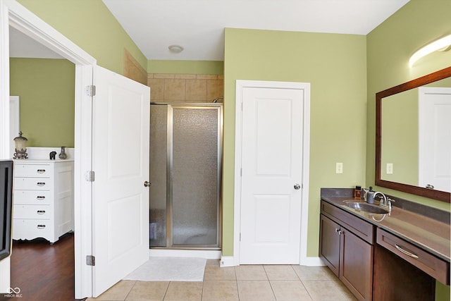 full bath featuring tile patterned flooring, baseboards, a shower stall, and vanity