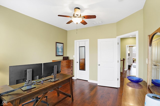 office with dark wood-style floors, baseboards, visible vents, and a ceiling fan