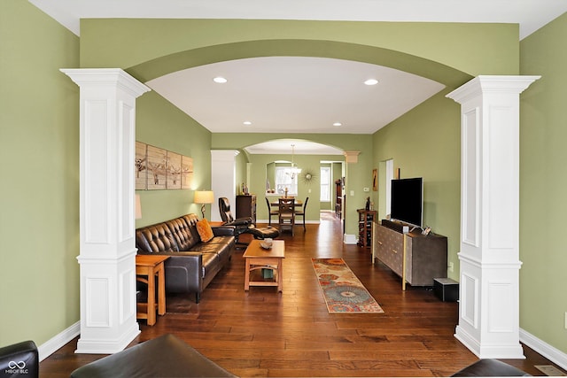 living area with baseboards, dark wood-type flooring, and ornate columns