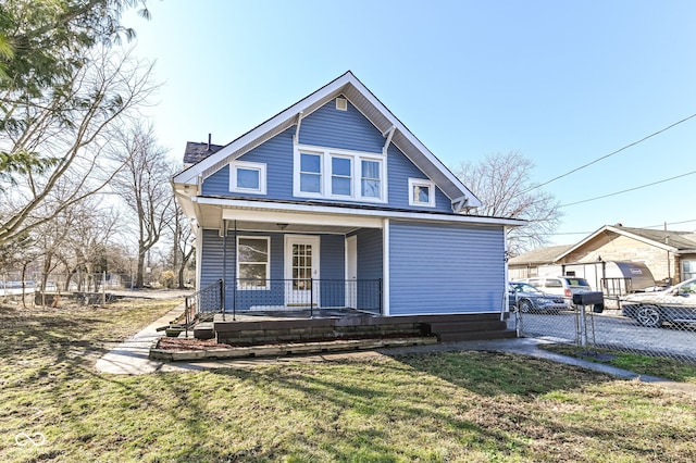 bungalow-style home with covered porch, fence, and a front lawn