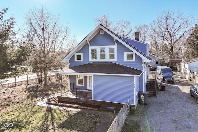 rear view of house with a porch, a shingled roof, a chimney, and fence