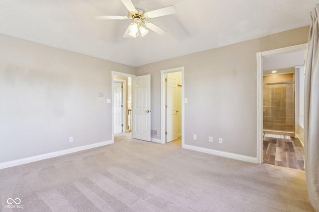 unfurnished bedroom with light colored carpet, connected bathroom, baseboards, and ceiling fan